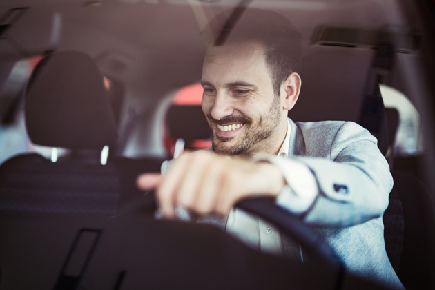homem branco sorrindo ao volante