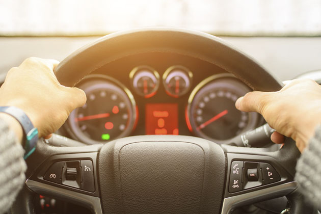 motorista com as mãos no volante de um carro