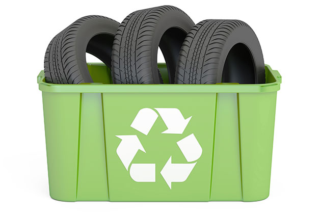 Pneus remoldados dentro de uma caixa verde de reciclagem