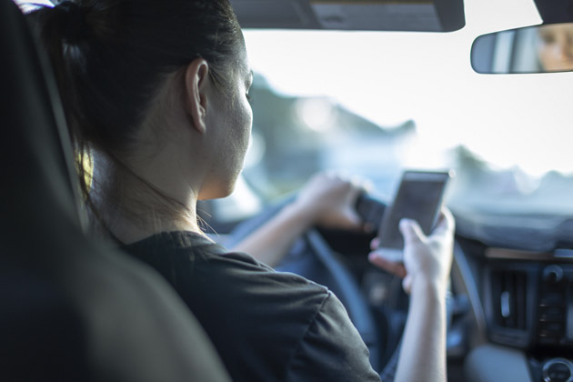 mulher fazendo uso do celular ao volante