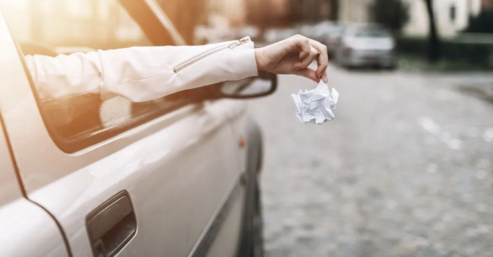passageiro do carro cometendo o ato de jogar lixo pela janela