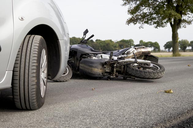 moto caída após acidente com carro estacionado atrás